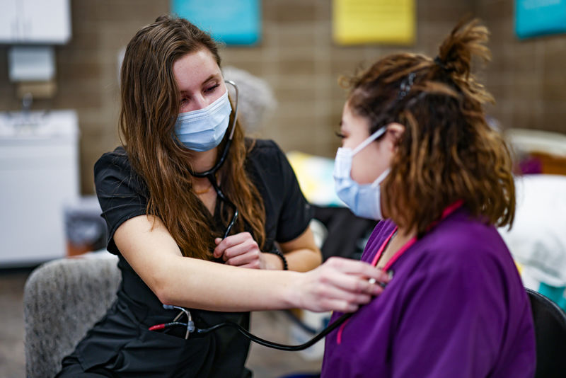 Nursing student checking a patient's heartbeat with a stethoscope during clinical training